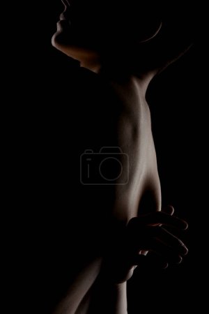 Foto de Retrato de una chica con el pelo corto sobre fondo oscuro. Slhouette contorno iluminado lateral de un cuerpo femenino. - Imagen libre de derechos