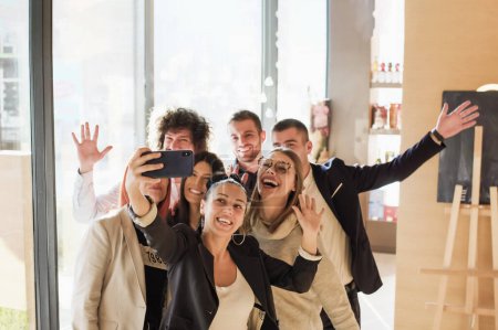A group of young business colleagues posing together and taking a self-portrait with a smartphone. Friends with happy smiling face expressions.