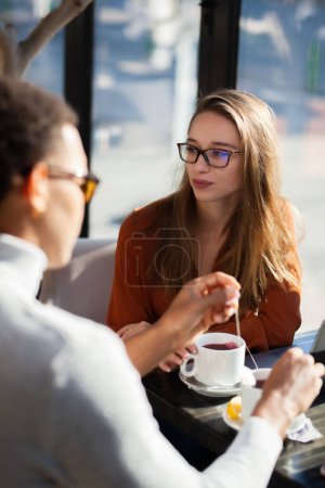 Friends in a restaurant talking smiling and drinking tea. Business colleagues having a meeting after work or during coffee break at a cafe bar.