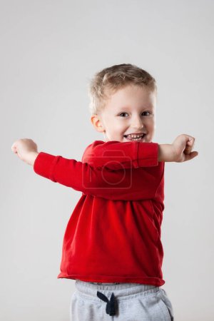 A little boy standing upright with his hands in the air