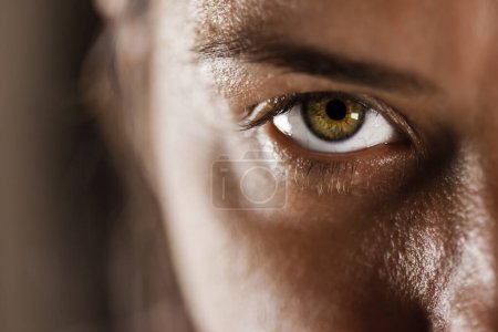 Dieses Bild fängt eine Nahaufnahme des Auges einer Frau ein und zeigt eine detaillierte Textur, natürliche Haut und eine lebendige Iris, die einen kraftvollen und fokussierten Blick widerspiegelt..