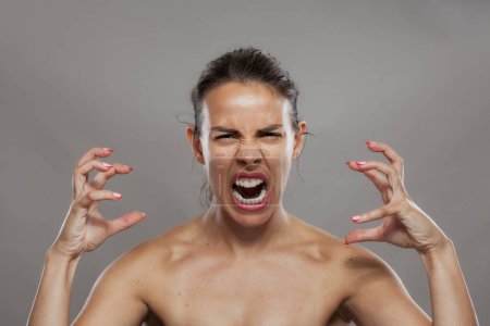Retrato de una joven enojada gritando frustrada, mostrando emoción extrema y expresión facial en un ambiente de estudio.