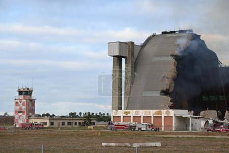 Photo for TUSTIN, CALIFORNIA - 7 NOV 2023: The MCAS Tustin Blimp Hangar on fire, with the control tower and fire crews. - Royalty Free Image