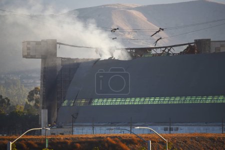 Téléchargez les photos : TUSTIN, CALIFORNIE - 13 NOV 2023 : Une éruption au-dessus des portes est du hangar à dirigeables Tustin du MCAS, quelques jours après le début de l'incendie. - en image libre de droit