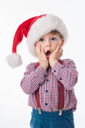 Téléchargez les photos : Drôle surpris bébé garçon avec cravate et bretelles et Père Noël chapeau rouge, concept de Noël de style de vie - en image libre de droit