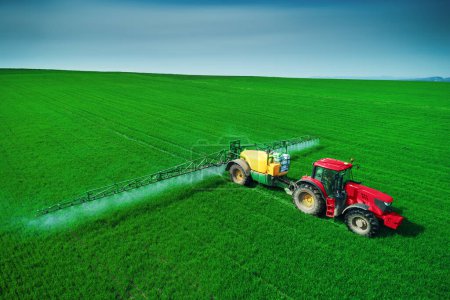 Photo for Aerial view of farming tractor plowing and spraying on field. - Royalty Free Image
