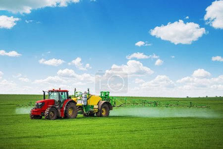 Téléchargez les photos : Tracteur pulvérisation d'engrais pulvérisation de pesticides sur champ vert, concept de fond de l'agriculture. - en image libre de droit