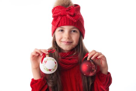Foto de Santa mujer con bolas de árbol de Navidad, niña en vestido rojo sombrero y bufanda posando con decoración bauble vacaciones - Imagen libre de derechos