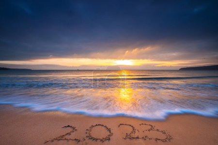 Téléchargez les photos : Bonne année 2023 voyage, sport, concept de méditation, lettrage texte sur la plage de sable de l'océan au lever du soleil. Coucher de soleil sur la mer de 2022. - en image libre de droit