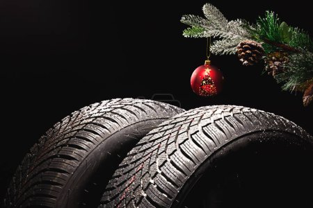Photo for Winter Car tire for snow and Christmas tree ball and decoration isolated on black background. New automobile tyre for snowy road. - Royalty Free Image