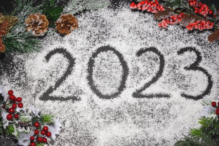 Foto de Nuevo año 2023 texto escrito en nieve con decoración de árbol de Navidad, conos de abeto y bayas silvestres con copos de nieve - Imagen libre de derechos
