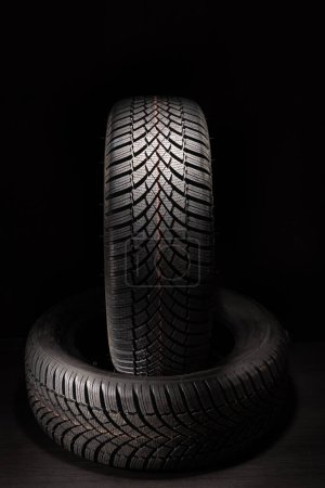 Téléchargez les photos : Car tire, new tyre on black background with copy space for text - en image libre de droit