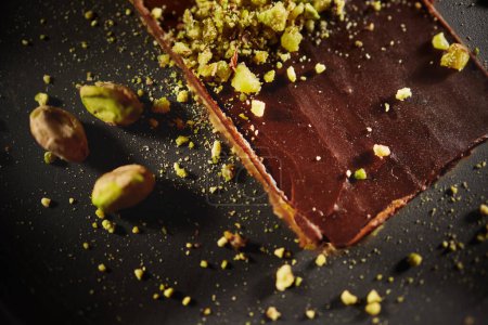 Foto de Chocolate cake with walnuts and pistachio isolated on black background. Pastry from homemade bakery - Imagen libre de derechos