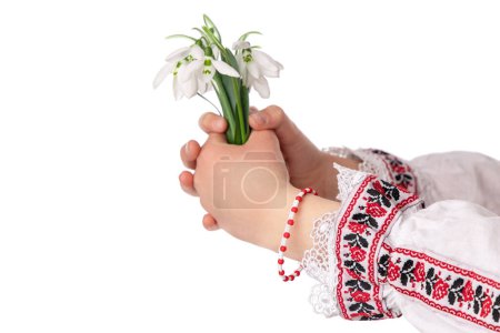 Photo for Bulgarian girl in traditional folklore costumes with snowdrop flowers and handcraft wool bracelet martenitsa symbol of Baba Marta, spring and Easter holiday - Royalty Free Image