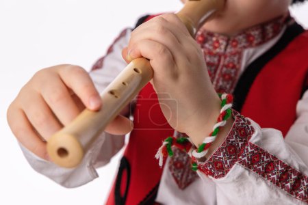 Photo for Bulgarian boy in traditional ethnic folklore costume, martenitsa and wooden flute, Bulgaria - Royalty Free Image