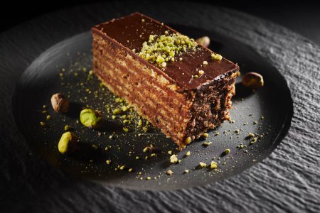 Photo for Chocolate cake with walnuts and pistachio isolated on black background. Pastry from homemade bakery - Royalty Free Image