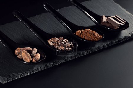 Téléchargez les photos : Barre chocolatée, cacao en poudre, fèves et pointes de cacao, tas de cuillères en bois, fond chocolat - en image libre de droit