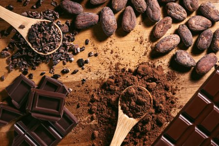 Téléchargez les photos : Barre chocolatée, cacao en poudre, fèves et pointes de cacao, tas de cuillères en bois, fond chocolat - en image libre de droit