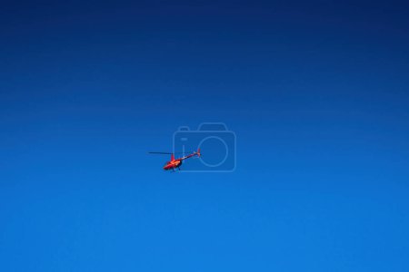Foto de Helicóptero rojo vuela en cielo azul claro - Imagen libre de derechos