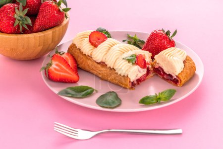 Photo for French eclair grazed with chocolate and fruity strawberry cream or sweet Italian profiteroles and fresh juicy strawberries, pastry cake food on pink backgroun - Royalty Free Image