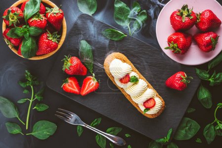 Téléchargez les photos : Éclair française pâturée de chocolat et de crème de fraise fruitée ou de profiteroles italiennes douces et de fraises juteuses fraîches, backgroun frais d'été - en image libre de droit
