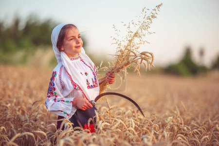 Photo for Farmer woman bulgarian little girl in ethnic folklore costume hold golden wheat straws and sickle in harvest field, harvesting and agriculture in Bulgaria - Royalty Free Image