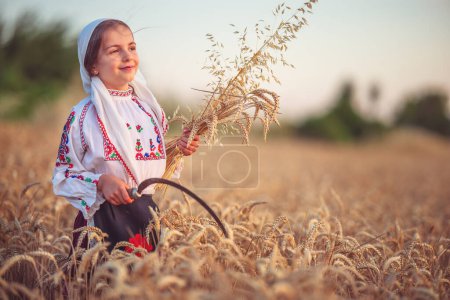 Foto de Mujer campesina bulgara niña en traje folclórico étnico sostienen paja de trigo dorado y hoz en el campo de cosecha, cosecha y agricultura en Bulgaria - Imagen libre de derechos