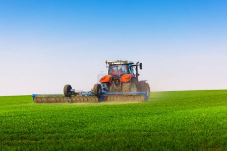 Photo for Tractor with a roller tillage on spring field. Soil rolling supports germination and is the basis for good harvesting, organic farming and agronomy - Royalty Free Image