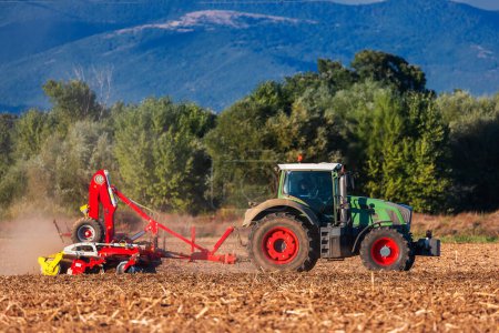 Téléchargez les photos : Agriculteur en tracteur préparant des terres avec cultivateur de lit de semence - en image libre de droit