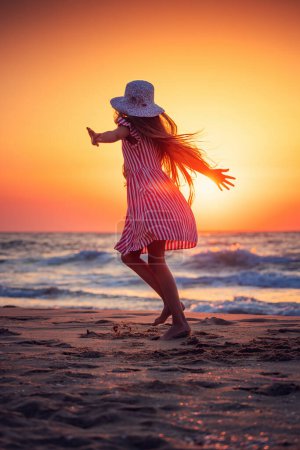 Foto de Salida del sol playa del océano y niña feliz caminando y bailando en la orilla arenosa - Imagen libre de derechos