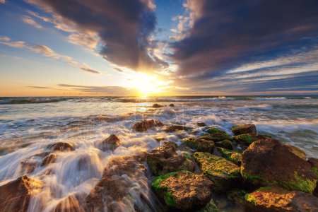 Foto de Olas salpicaduras de oro, playa rocosa orilla y horizonte del mar amanecer - Imagen libre de derechos