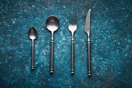 Photo for Dark blue old vintage backdrop with kitchen utensils fork, knife, spoon and copy space for text, - Royalty Free Image