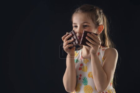 Photo for Chocolate and pretty hungry little woman portrait. Beautiful girl ready to eat chocolate bar. - Royalty Free Image