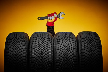 Foto de Neumáticos de invierno y mano de mecánico con llave inglesa, destornillador, servicio de automóvil - Imagen libre de derechos