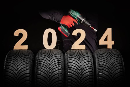 Photo for Winter car tires service and hand of mechanic with wheels crewdriver, 2024 happy new year on black background. - Royalty Free Image