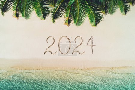 Foto de Feliz año nuevo concepto de playa, 2024 escrito en la arena. Vacaciones de verano en la isla tropical. Palmeras y olas marinas. - Imagen libre de derechos