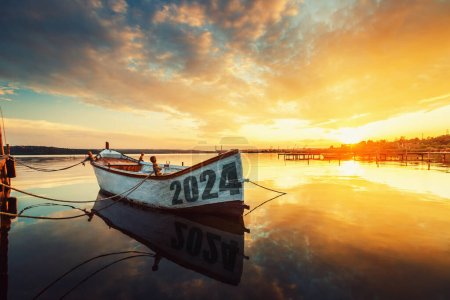 Téléchargez les photos : 2024 concept Bateau de pêche sur le lac Varna avec un reflet dans l'eau au coucher du soleil. - en image libre de droit