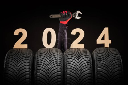 Photo for Winter car tires service and thumbs up hands of mechanic and text 2024 happy new year on black background - Royalty Free Image
