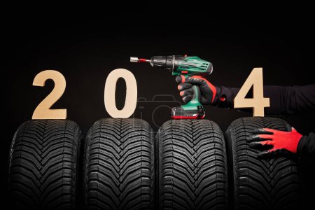 Photo for Car tires, winter wheels, isolated new tyres, happy new year 2024 black background . - Royalty Free Image