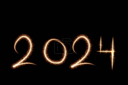 Foto de 2024 texto feliz año nuevo escrito con chispa fuegos artificiales sobre fondo negro, fondo estacional con bengalas - Imagen libre de derechos