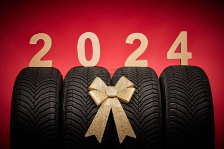 Photo for Car tires, new tyres, winter wheels isolated on christmas red background with text happy new year 2024. - Royalty Free Image