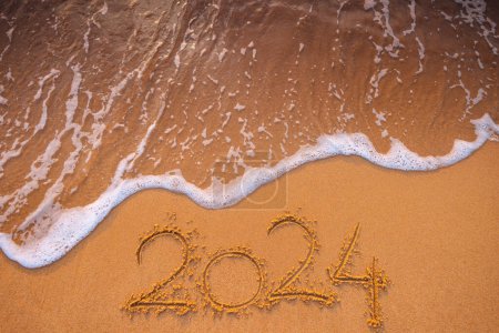 Téléchargez les photos : Bonne année 2024 concept, lettrage sur la plage. Texte écrit sur la plage au lever du soleil. - en image libre de droit