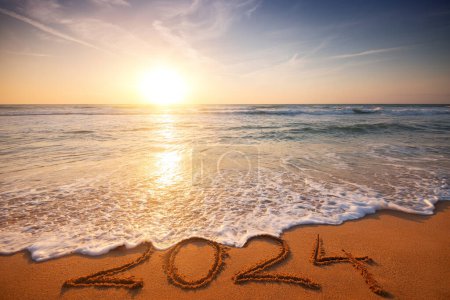 Foto de Feliz Año Nuevo 2024 concepto, letras en la playa. Texto escrito en la playa al amanecer. - Imagen libre de derechos