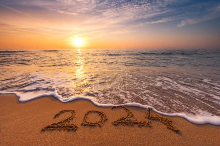 Foto de Feliz Año Nuevo 2024 Texto sobre la arena tropical de la playa, el amanecer del mar Caribe y las olas en la orilla. - Imagen libre de derechos
