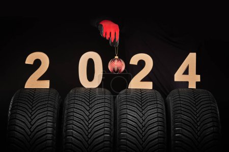 Téléchargez les photos : Pneus de voiture d'hiver, main de mécanicien homme avec boule de Noël, 2024 fond - en image libre de droit
