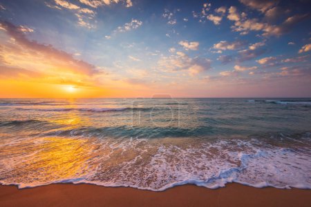 Téléchargez les photos : Littoral océanique, lever de soleil sur le bord de la mer avec des vagues éclaboussantes sur la plage de sable - en image libre de droit