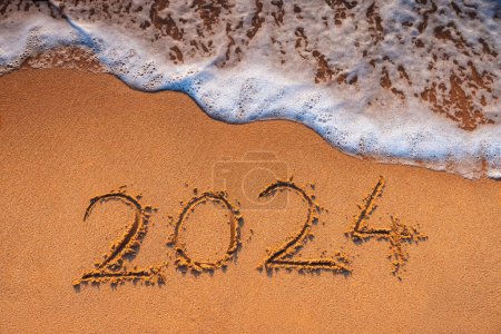 Téléchargez les photos : Bonne année 2024 concept, lettrage sur la plage. Texte écrit sur la plage au lever du soleil. - en image libre de droit
