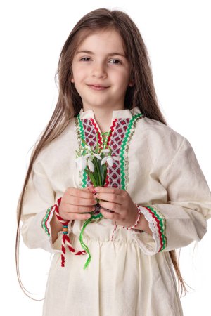 Foto de Chica búlgara con gotas de nieve flores de primavera ramo de vestir tradicional folklore étnico y blanco pulsera de hilo rojo martenitsa martisor, Bulgaria - Imagen libre de derechos