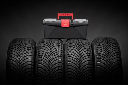 Foto de Neumáticos para automóviles, neumáticos de invierno con caja de herramientas con instrumentos para reparación de automóviles aislados sobre fondo negro - Imagen libre de derechos