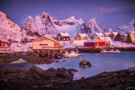 Foto de Pueblo pesquero noruego con casas de rorbu rojo, picos de montaña y costa marina paisaje invernal, islas Lofoten, Noruega - Imagen libre de derechos